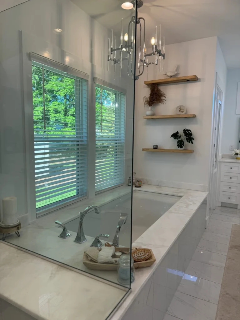 A tiled bathtub below a chandelier light fixture